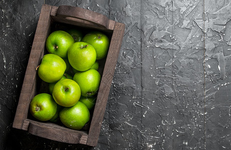 绿苹果放在木箱里黑背景图片