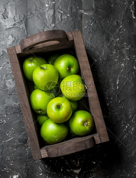 绿苹果放在木箱里黑背景图片