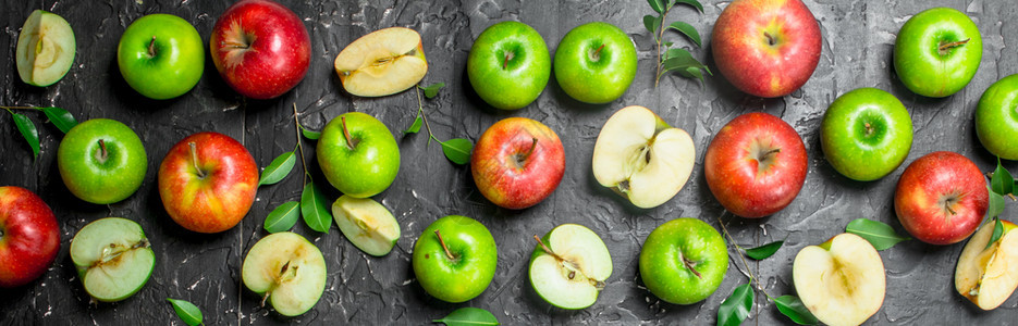 绿色和红多汁苹果配有叶子和苹果切片黑色生锈背景绿色和红多汁苹果配有叶子和苹果切片图片