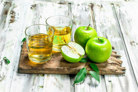 苹果汁在木板上的玻璃杯里在白色木板背景上苹果汁在木板上的玻璃杯里图片