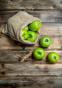 灰木本底的旧袋子里有多汁的绿苹果图片