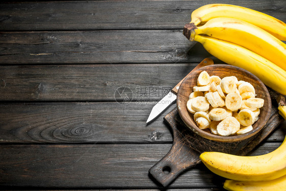 用刀砍板上的香蕉和片用刀砍板上的香蕉和片用黑木头背景板上的香蕉和片用刀砍板上图片