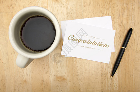 祝贺纸条卡笔和咖啡杯放在木头背景上图片
