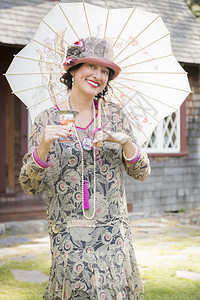 美丽的1920年代身着阳伞和葡萄酒肖像杯的穿衣女孩图片