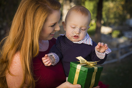 年轻母亲和婴儿抱着圣诞礼物图片