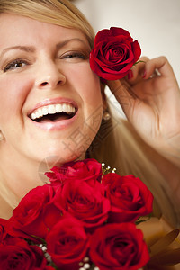 美丽的女人带着一束红玫瑰将只放在她耳朵上图片