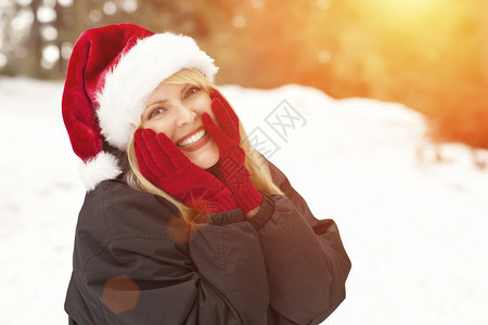 穿着金发女人的漂亮圣诞帽冬天在雪上玩得开心图片
