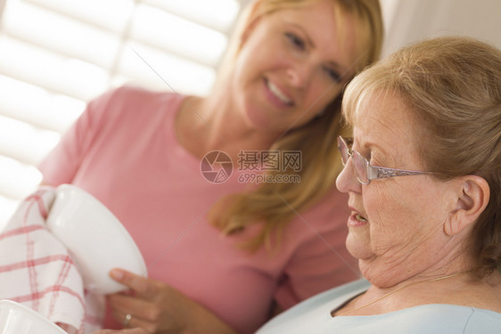 微笑着的成年老人和轻的女儿在厨房水槽里说话图片