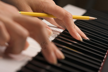 妇女数字钢琴键上手持铅笔的指图片
