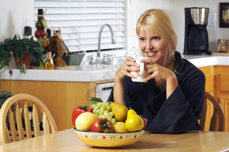 美丽的年轻成功女子在家里享受一杯咖啡在厨房微笑着喝咖啡的女人图片