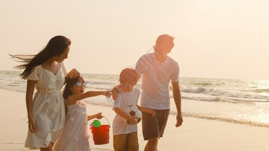 父母和孩子在日落时分一起去海边散步图片