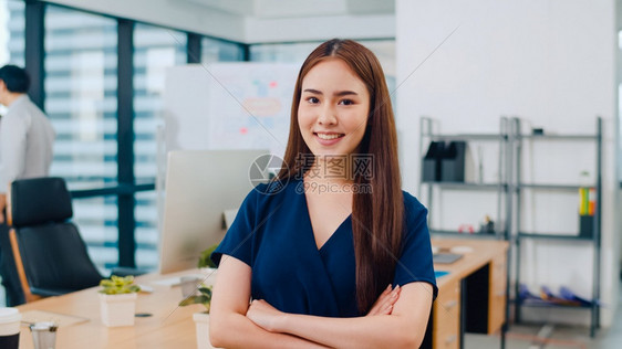 美丽的女执行官聪明的随意穿戴看着镜头微笑手在现代办公场所交叉年轻女士站在当代会议室图片