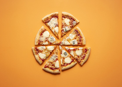 芝士比萨在橙色无缝背景上被切成平整的一块铺四芝士比萨图片