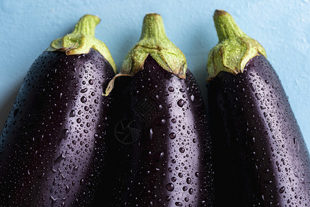 喷洒着水的深紫色茄子3个贴近视野新鲜采摘的蔬菜被水滴覆盖图片
