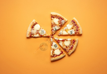 面顶有平披萨切片橙色背景平面上有一块薄饼素食披萨有四种奶酪和番茄酱作为奶油土制披萨图片