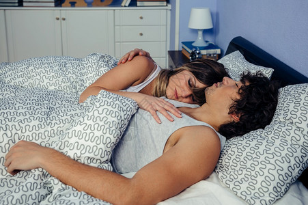 睡在家中床上的年轻夫妇图片