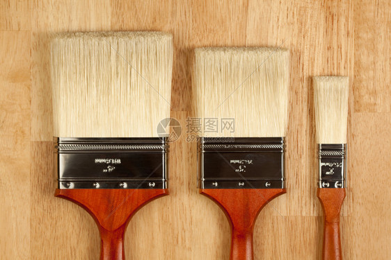 木质表面有三种不同尺寸的新油漆刷子图片