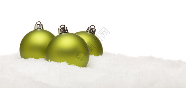 三个绿色圣诞装饰品在雪片上白色背景的雪片上图片