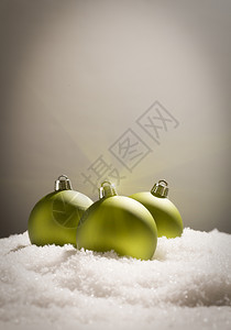 灰色背景的雪片上绿色圣诞装饰品图片