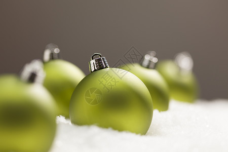 灰色背景的雪片上绿色圣诞装饰品图片
