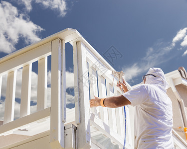 身穿面部保护的画家喷洒一副房子的甲板图片