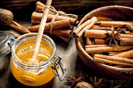 新鲜蜂蜜和肉桂棒放在碗里生锈的背景新鲜蜂蜜和肉桂棒放在碗里图片