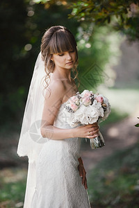 美丽的年轻微笑新娘拿着盛大婚礼花束和粉红色的玫瑰婚礼在和绿色的调子上举行婚礼日背景图片