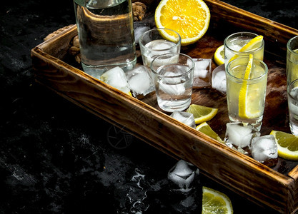 伏特加柠檬和冰放在木制餐具上黑板图片