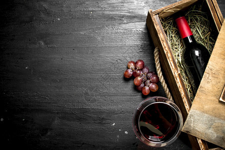 红酒瓶装在旧盒子里葡萄枝在黑板上红酒瓶装在葡萄枝的旧盒子里图片