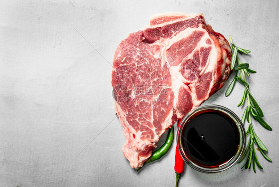 一堆新鲜生牛肉含迷迭香和辣椒生锈背景的新鲜生牛肉图片