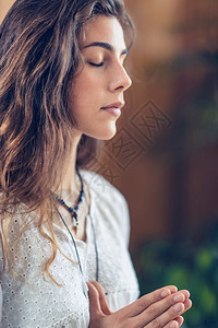 美丽的年轻女站在她的眼睛近冥想同时练习瑜伽用双手祈祷姿势图片