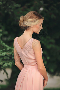 金发女孩穿着粉红裙子的时髦发型春公园年轻女肖像侧观金发女孩粉红裙子的时髦发型图片