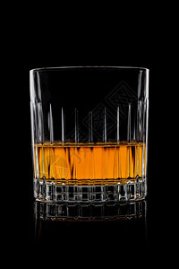 威士忌在水晶优雅的玻璃杯里黑色背景和反射图片