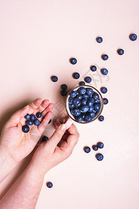 不可辨认的妇女一只手握着杯咖啡新鲜蓝莓另一对水果图片