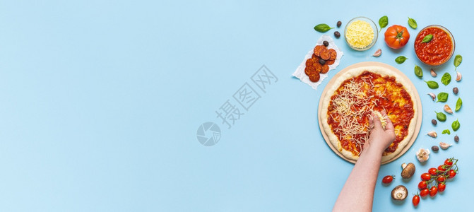 妇女手把奶酪放在比萨上顶层视图由厨师一步地做比萨饼上面是蓝桌的比萨饼成分图片