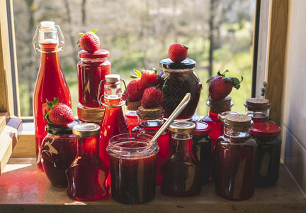一大堆瓶子和罐里面有自制的草莓糖浆和果酱在早上的阳光下厨房窗户里有草莓果酱罐机草莓糖浆图片