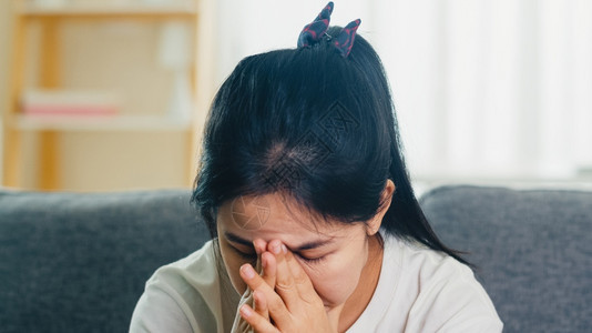 哭泣的亚洲女商人强调坐在沙发上头痛背景图片