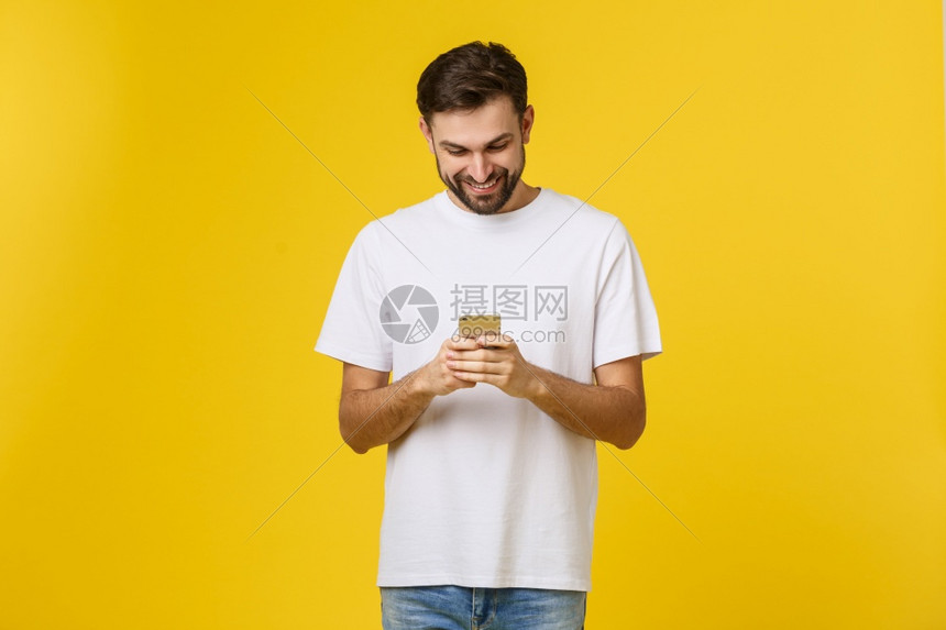 来自朋友的好消息自信穿牛仔裤衬衫年轻英俊男子在黄色背景下持有智能手机朋友的好消息自信穿牛仔裤衬衫年轻英俊男子在黄色背景下持有智能图片