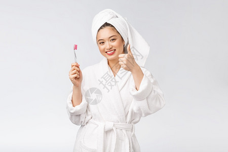 有牙刷和的亚洲人快乐女在浴袍的早晨心情中图片