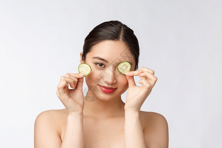 美丽的亚洲女子拿着黄瓜片遮住眼睛图片