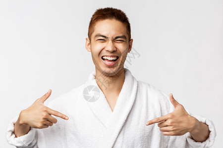 美丽娱乐和休闲概念成功快乐英俊的亚洲男子肖像指着自己笑说话自己的成就穿浴袍白色背景美丽英俊的亚洲男子肖像穿着浴袍白色背景图片