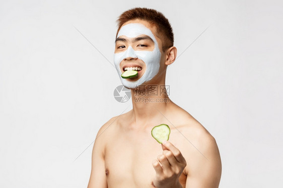 美护肤和温泉概念笑裸的亚洲男子在化妆品中的肖像面部罩用来治疗腹肌吃黄瓜建议咬人在自我持隔离期间放松美护肤和温泉概念笑裸的亚洲男子图片