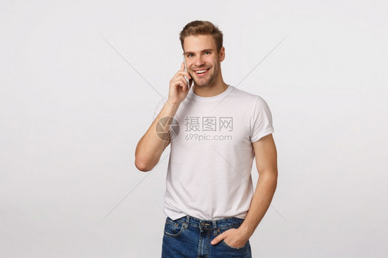 英俊的无忧心笑脸大男子汉头发金胸罩闲聊电话手持智能机近耳笑着相白色背景商业技术和现代生活方式概念金发棕色手持智能机图片