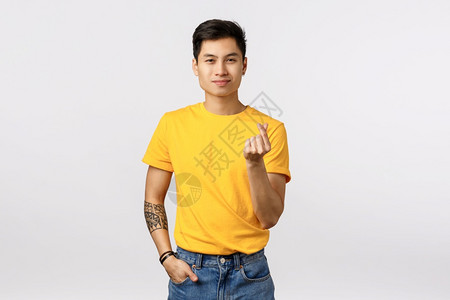 穿着黄色t恤的可爱亚洲潮人男子展示韩国人的心脏手势和微笑傻地承认爱表达或钦佩站立高雅的白色背景关系概念图片