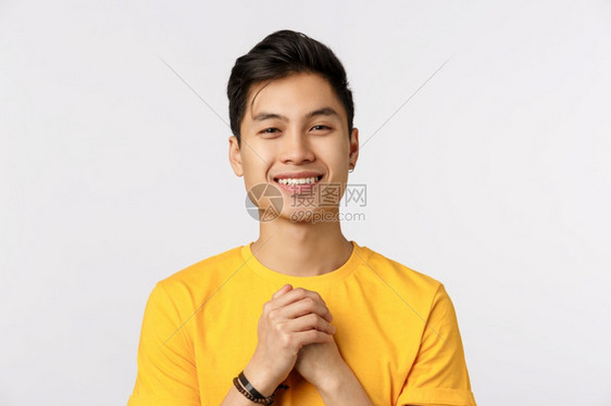 可爱的时装男穿着黄色t恤手放在胸前感恩或触的姿势上笑高兴地得到赞美白背景图片