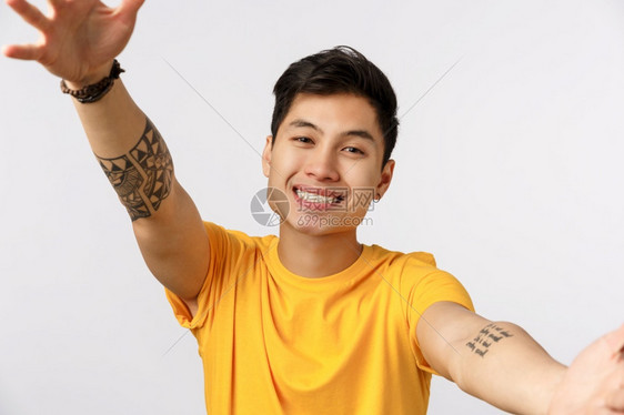 穿着黄色t恤的可爱年轻千亚洲男子亲手抱想要拥或最亲密的朋友笑着可爱和快乐的笑容站立白色背景可爱图片