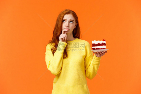 关心计算热量饮食想吃美味蛋糕拿着甜点抬起看着周到和麻烦橙色墙壁担心拿着甜点橙色墙图片