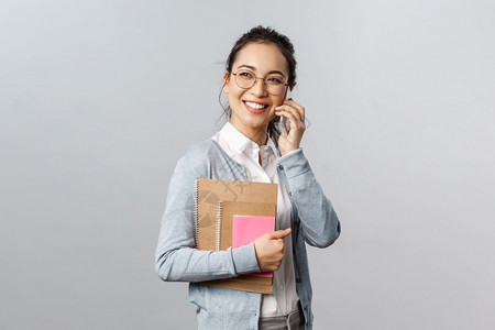 带着眼镜的女孩手上抱着笔记本一边打电话图片