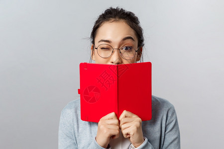 戴着眼镜的女孩拿着红色的笔记本图片