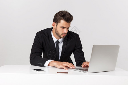 在办公室工作的英俊商人用笔记本电脑的前视线用笔记本电脑孤立的白人图片